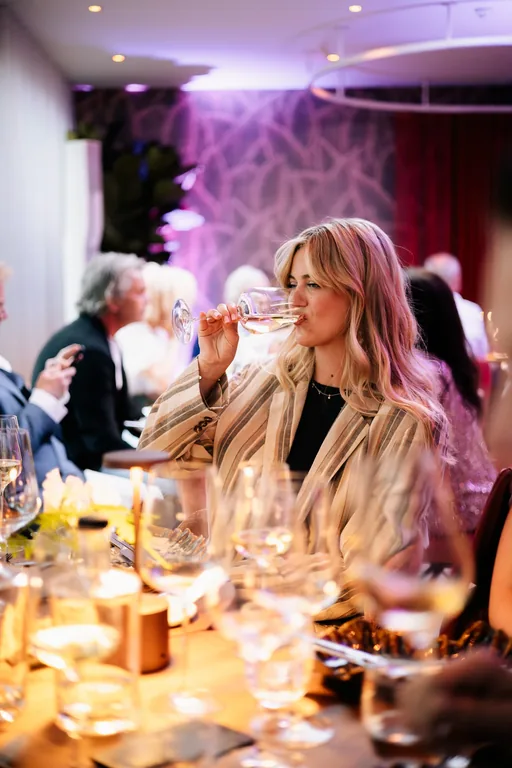 Een gast met een wijnglas aan een gedekte tafel bij Restaurant Amante.