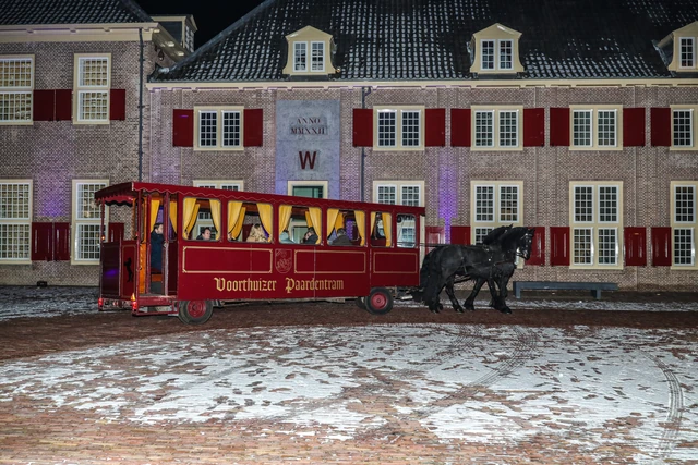 Een rode paardentram voor een besneeuwde bakstenen gevel.