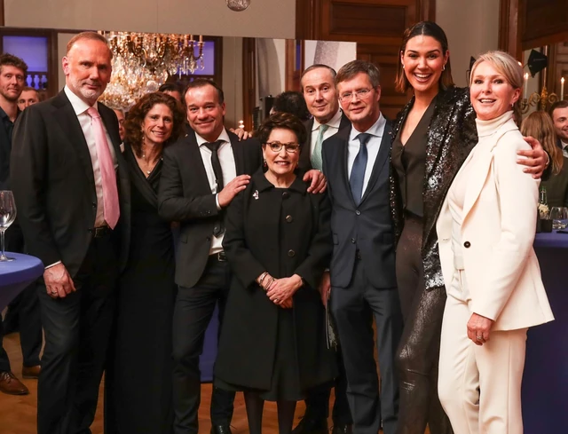 Groepsfoto van gasten in een zaal met kroonluchters.
