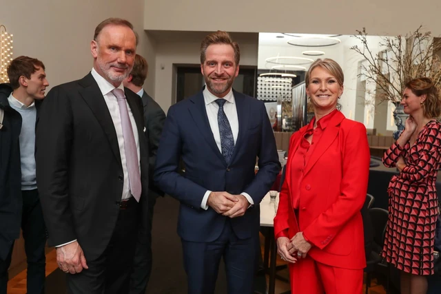 Groepsfoto van drie gasten in een lichte ontvangstruimte.