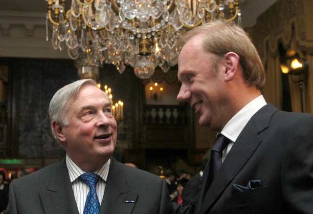Twee gasten zijn met elkaar in gesprek onder een kroonluchter.