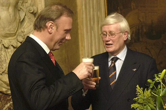 Twee gasten staan tegenover elkaar met een glas in de hand.