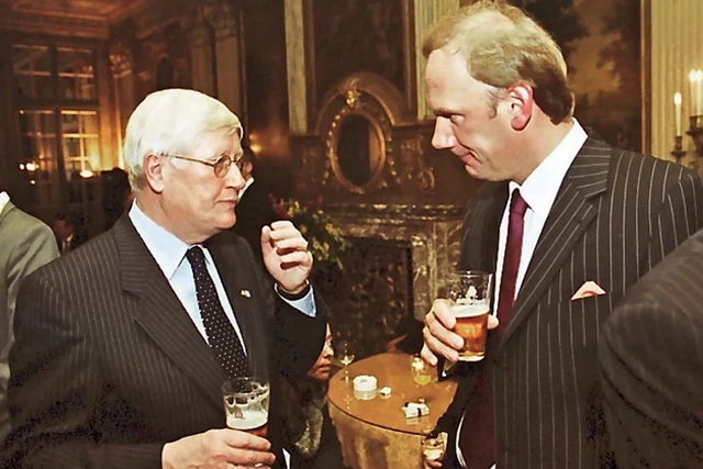 Twee gasten staan met een drankje in gesprek bij een hoge tafel.
