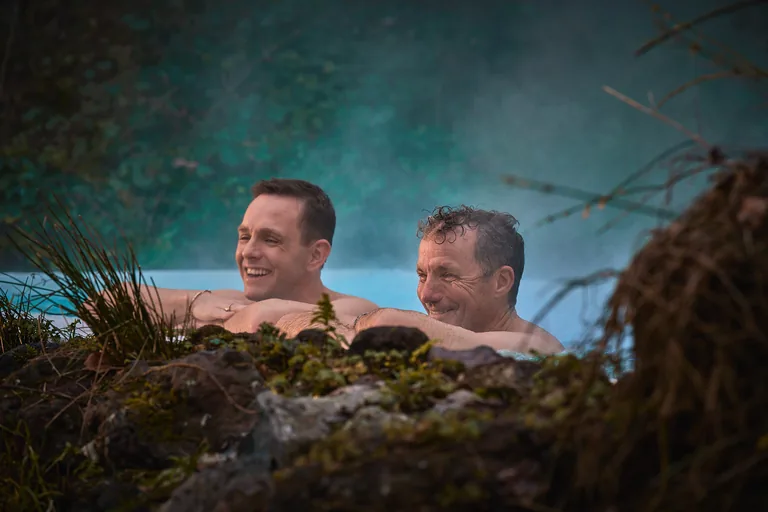Twee gasten in een buitenbad tussen het groen.